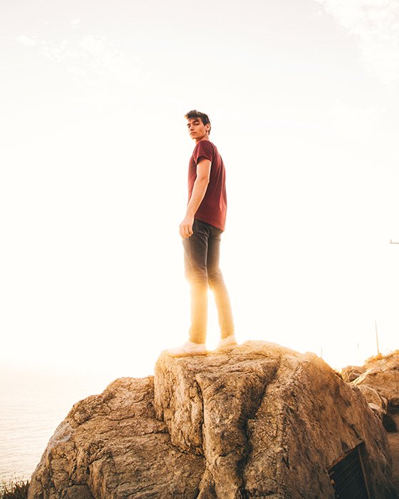 Man posing on a cliff during golden hour lights.
