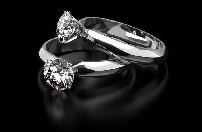 Jewelry product photo of two diamond engagement rings on black background