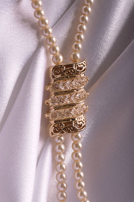 pearl necklace on silk background with a golden medal