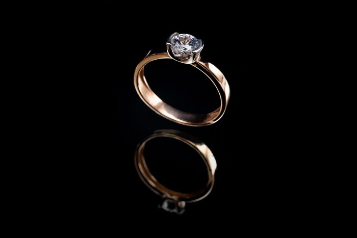 Jewelry product photo of a gold engagement ring on black background, and its reflection