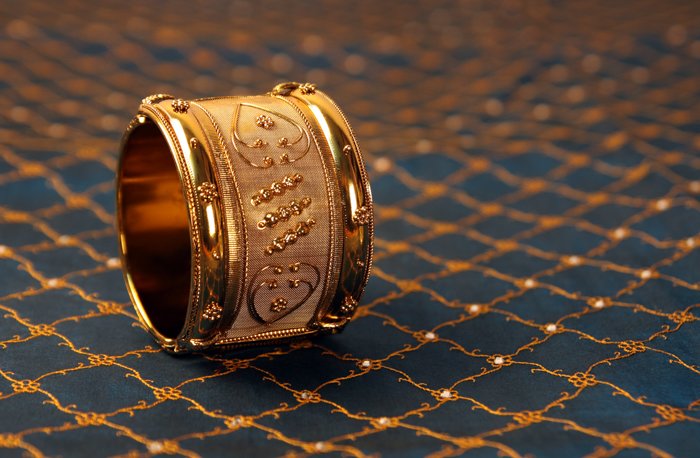 a gold bracelet on blue and golden fabric