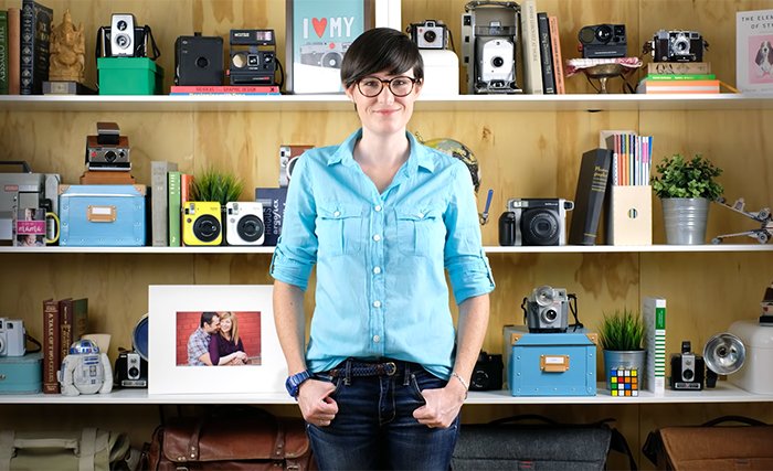 Photo of a woman standing in front of shelves full of cameras