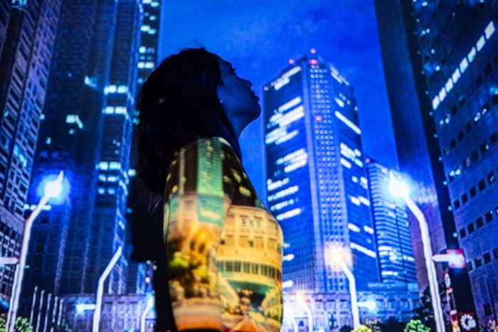 A portrait of a female model with a projected photo of a cityscape on her