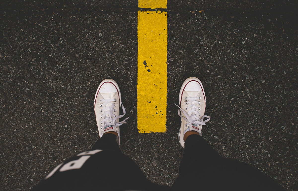 Legs and feet over a painted yellow line on the pavement with no shadows