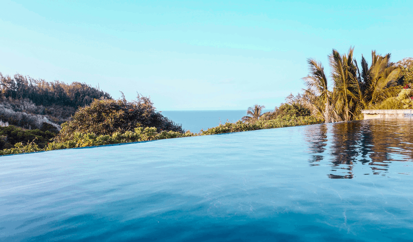 A photo of an outdoor resort pool with a blue hazy sky and foilage around it for the Sunny 16 Rule