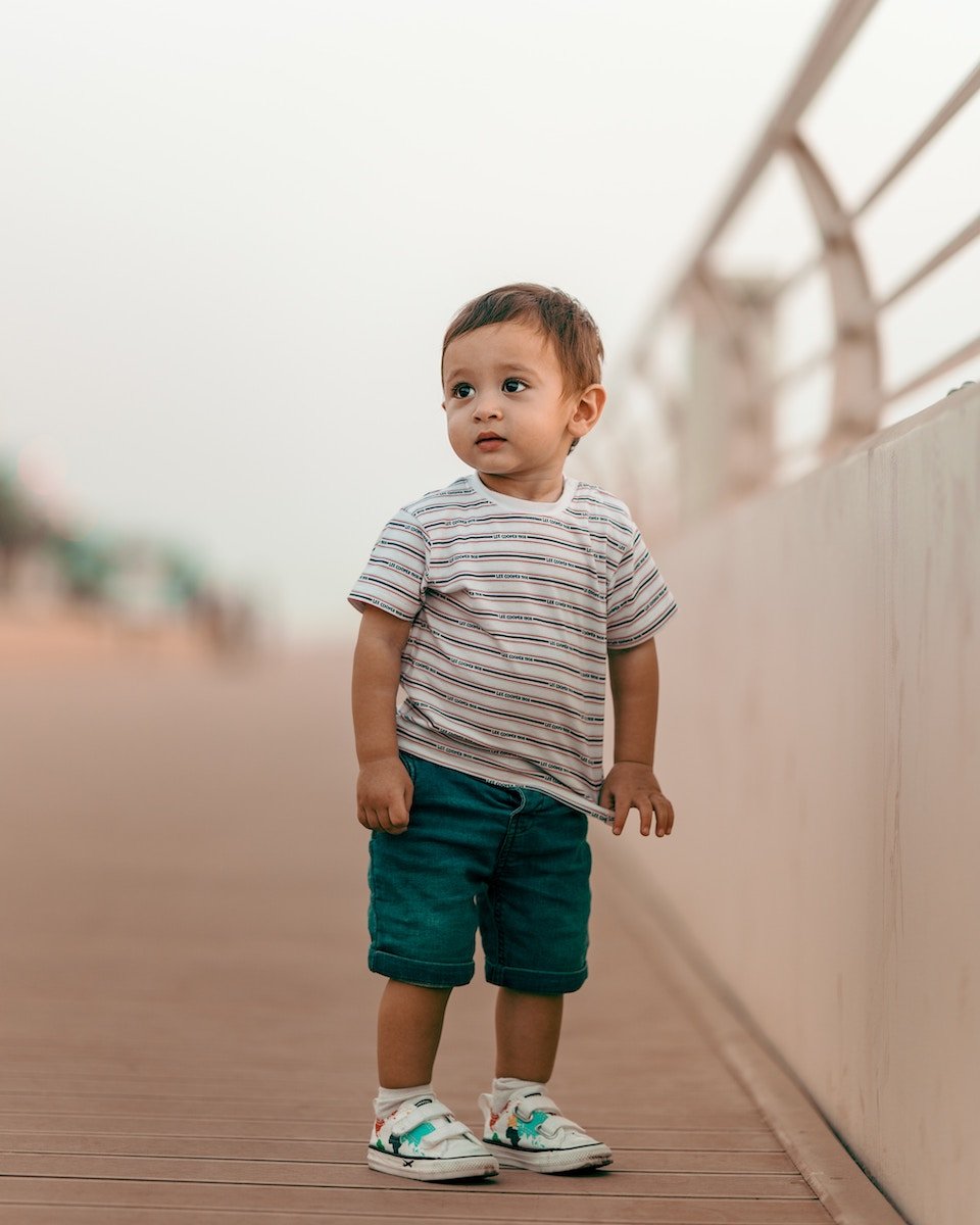 Toddler standing outside by a railing