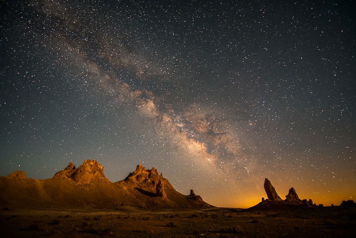 Night photo of the Milky Way appearing above mountains