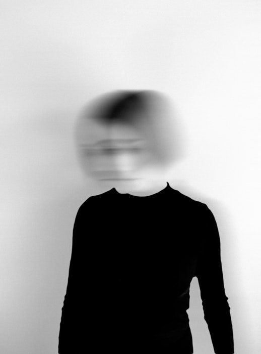 A black and white image of a woman with her head blurred