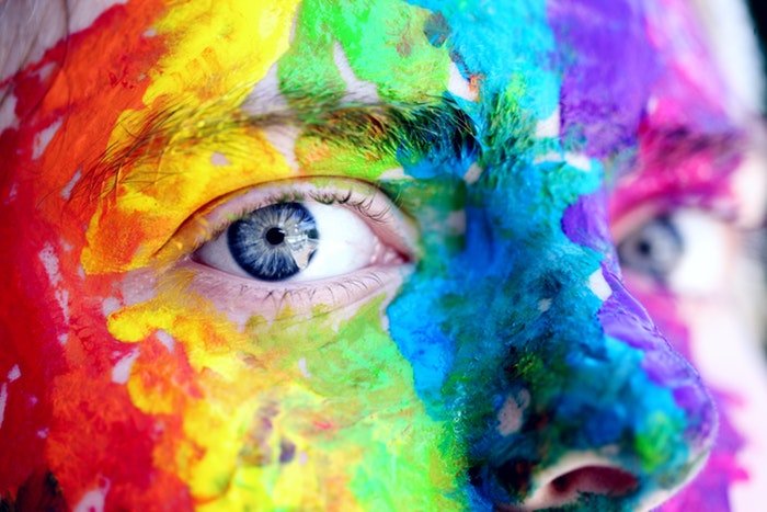 A close up of a persons face covered in colored Holi powder