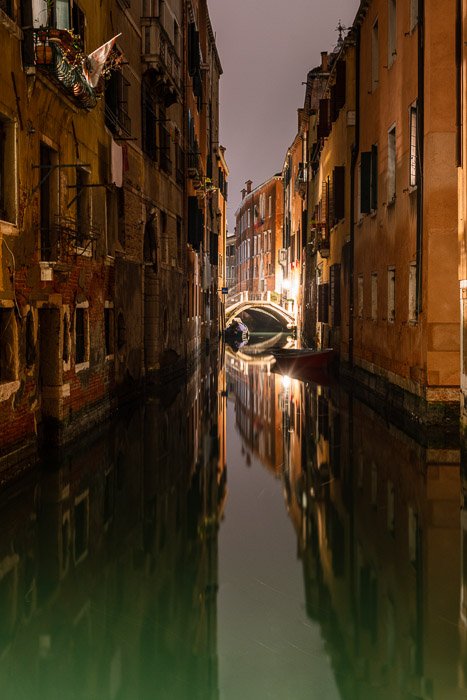 Broad scene of Venetian bridge and canal at night.
