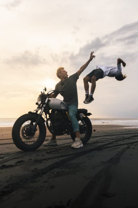 Photo of a guy on a motorcycle with a boy jumping from it