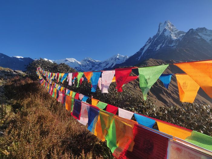 A sharp photo of a string of colorful flags with a mountain in the background