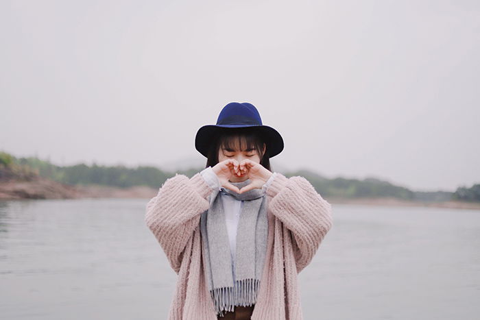 A woman making heart shape with her hands - self-love is more than just a photography trend