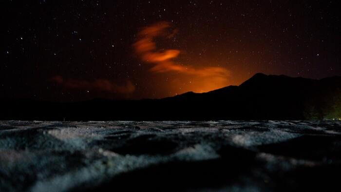 Silhouette of a mountain under the orange night sky