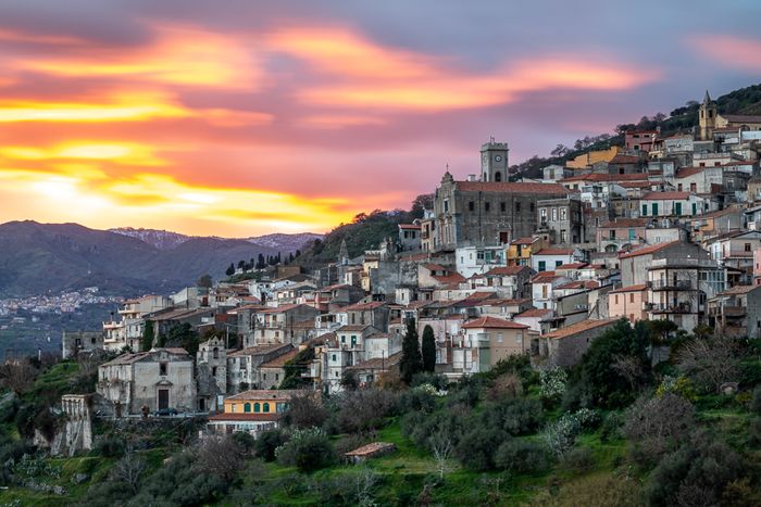 photo of a small village on a hill at sunset