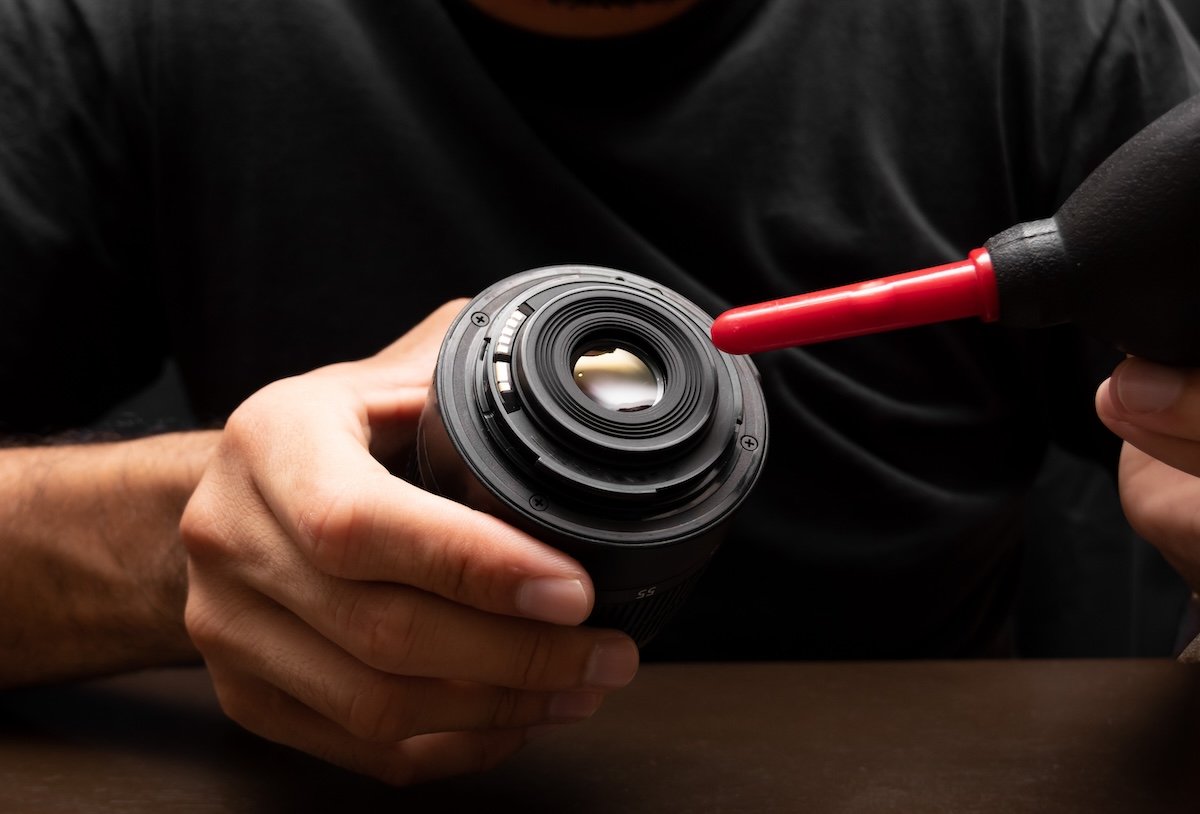 Cleaning a camera lens with an air blower to take sharp photos