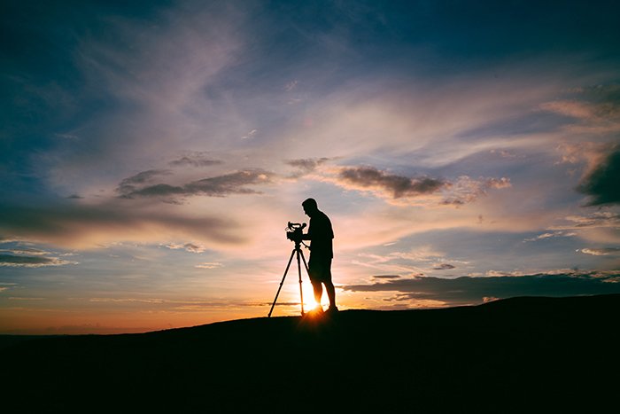 A photographer taking a landscape shot at evening time