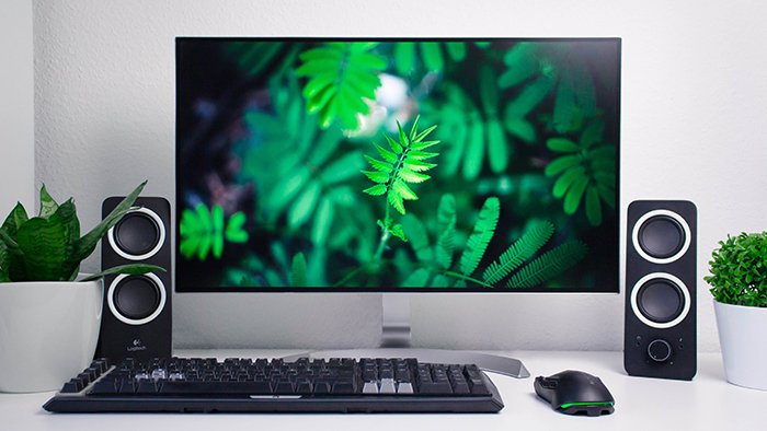 A photo editing monitor and desktop speakers and keyboard