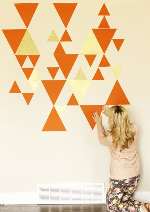 A woman creating a geometric wall pattern