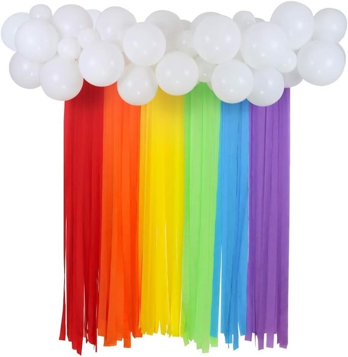 White balloons with rainbow streamers hanging below them to mimic clouds and a rainbow as a backdrop