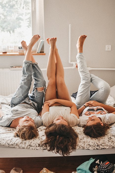 Three girls lying on a bed with legs in the air