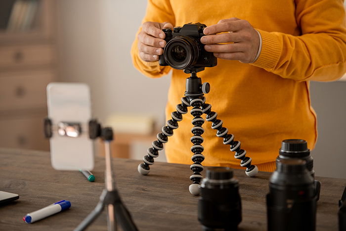 Hands of professional stock photographer fixing photocamera on tripod on table.