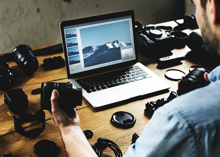 Photographer editing on his desktop with full of cameras.