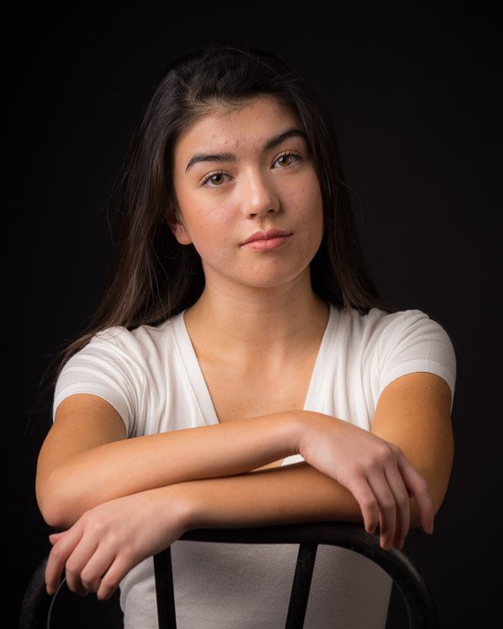 A brunette girl sitting backwards on a chair