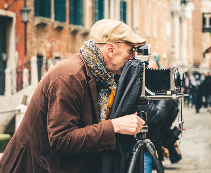 An old man taking street photos with a vintage camera