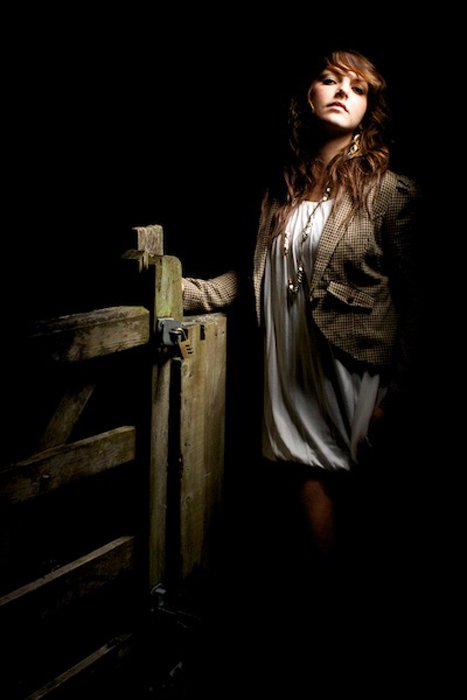 A woman posing in a barn in low light