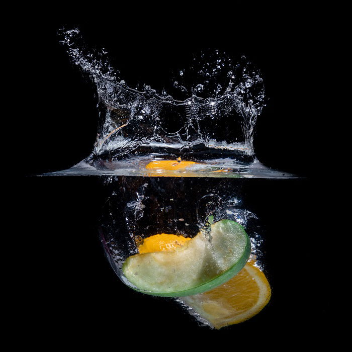 Orange peel and apple wedge dropped in water creating a splash for high-speed photography