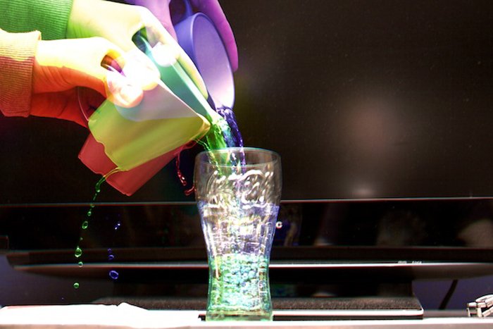 Harris effect of colorful hands pouring colorful water into a glass