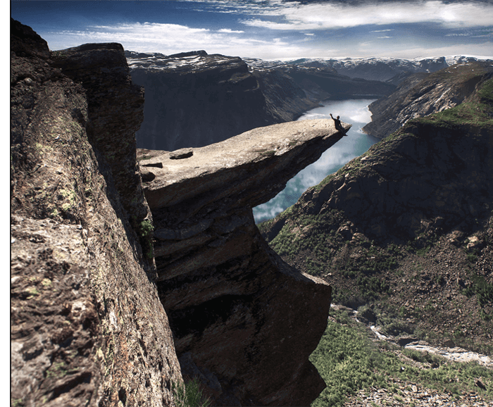 A man waving from the ledge of a cliff