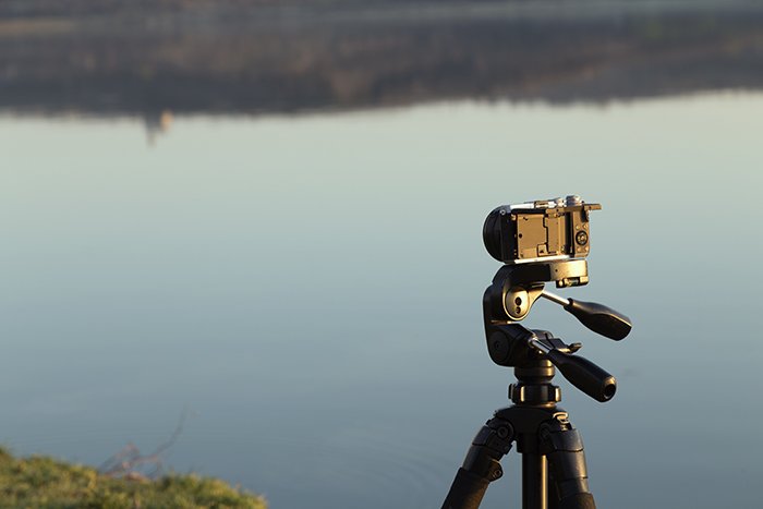 Camera on a tripod on the background of the lake.