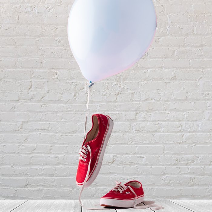 photo of red sneakers with a white balloon and a brick background