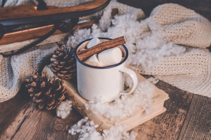 Someone drinking hot chocolate and reading under a warm blanket