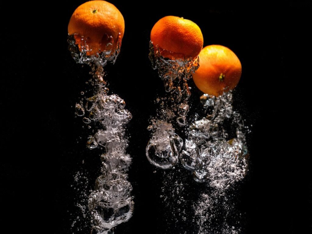 An inverted photo of oranges falling into water for high-speed photography