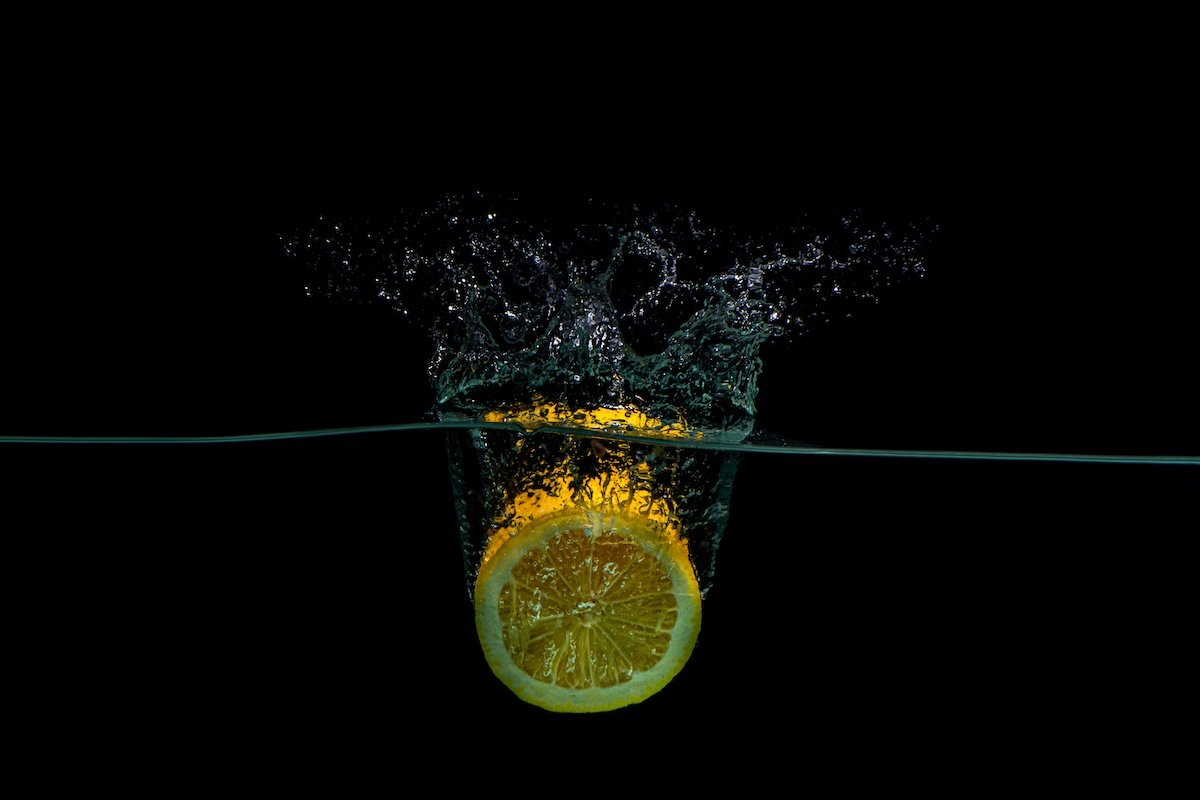 A lemon dropped in water creating a splash for high-speed photography