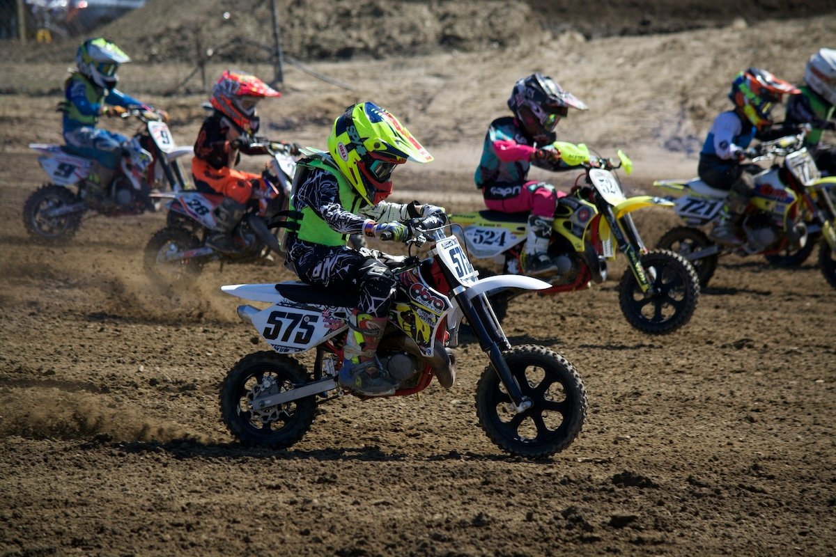 A group of kids on motorbikes racing across a muddy field for high-speed photography