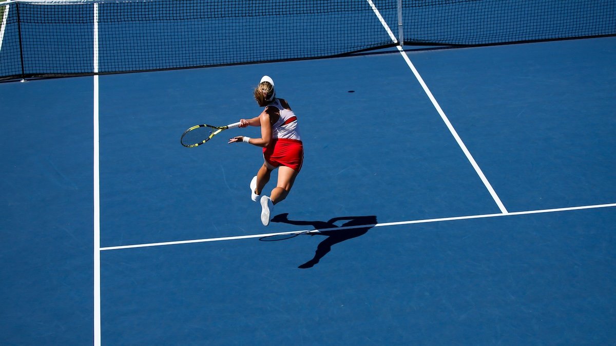 A tennis player on a court swinging a racquet for high-speed photography