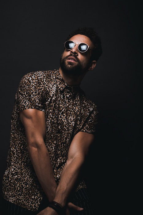 Man posing in front of a black wall in a photography studio