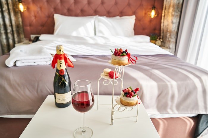 Champagne and cakes at the foot of a lavish hotel bed