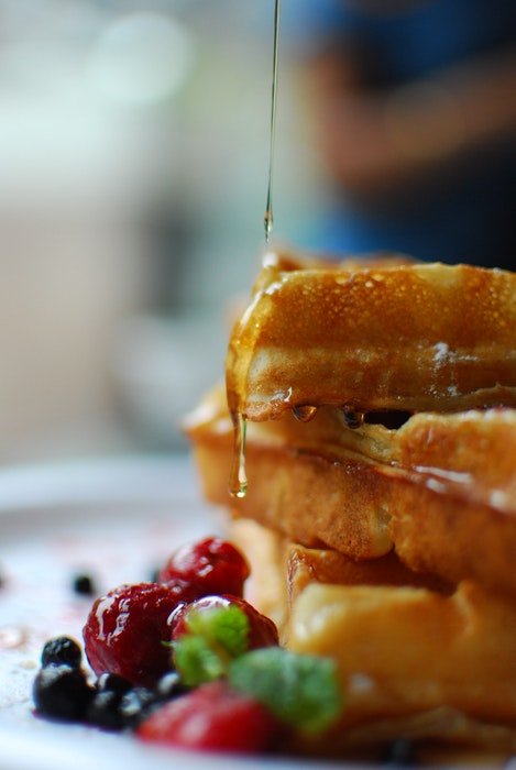 Closeup of syrup being drizzled onto a stack of pancakes