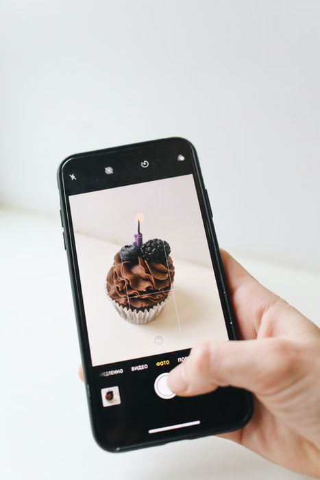 Una persona tomando una foto de un muffin de chocolate con una cámara de iphone