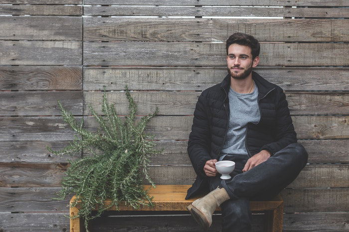 Man sitting on a bench with a plant 