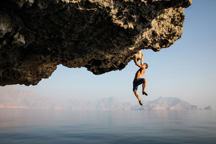 A man dangling from a cliff photo by Jimmy Chin