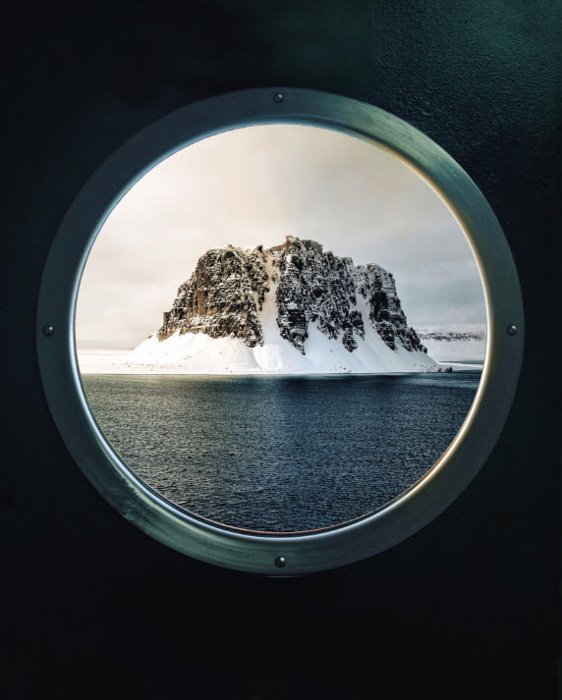 Iceberg seen through a ships porthole, photo by Simone Bramante
