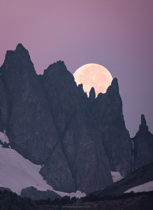 The moon behind craggy mountains, photo by Joshua Cripps