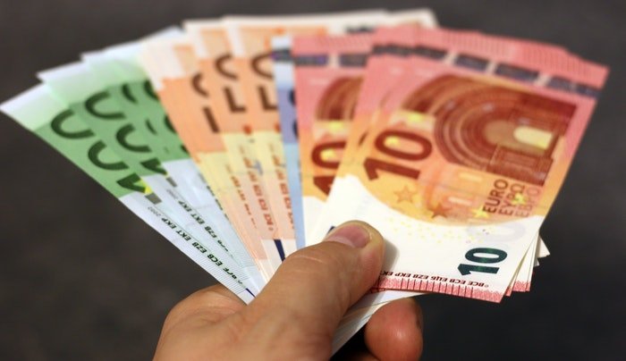 A hand holding a fan of euro notes