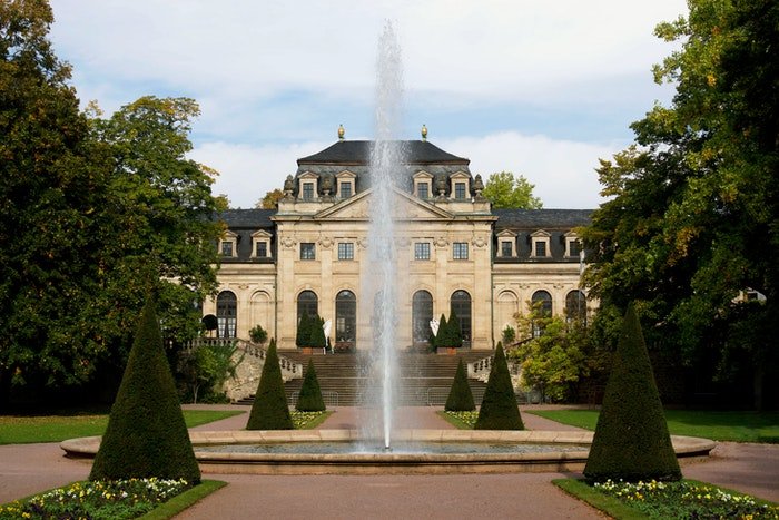 photo of a manor with a garden and a fountain in the foreground